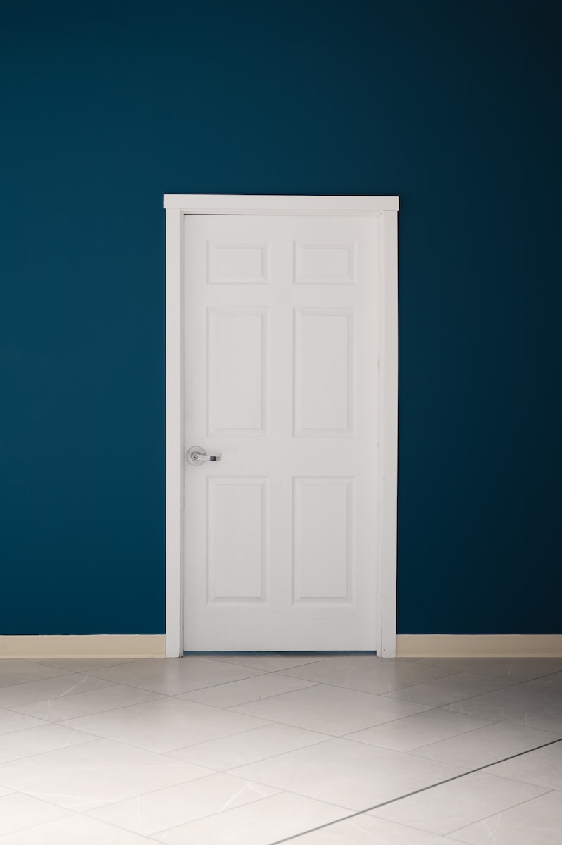 an empty room with a white door and a blue wall